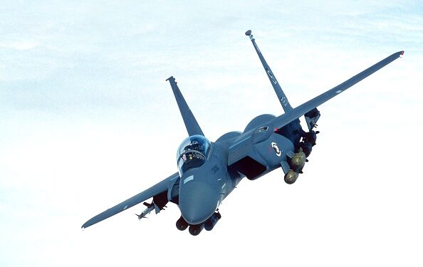 USAF Boeing F-15E Strike Eagle flying enroute above a layer of clouds with a full load of bombs