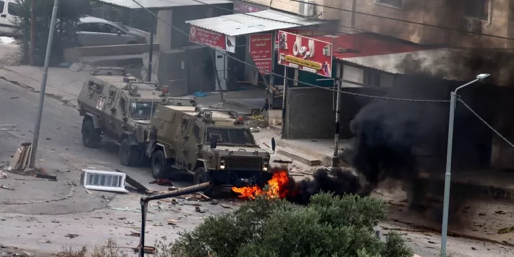 Tyres burn beneath Israeli security forces armoured vehicles during a raid in Jenin in the occupied West Bank on June 19, 2023. Israeli forces in the occupied West Bank killed three Palestinians, in a raid that saw seven Israeli security personnel wounded and rare helicopter fire as the army said it pursued "wanted suspects". (Photo by Jaafar ASHTIYEH / AFP)